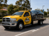 Towing Eastvale flatbed tow truck transporting a disabled sedan safely along the roadway for secure vehicle recovery