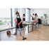 Vier Reinigungskräfte säubern ein modernes Büro mit Staubsauger, Lappen und Fensterputzern.