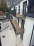 Zwei neue Balkone aus Holz und Metall, an weißer Hausfassade montiert, mit Terrassenfliesen davor.