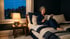 Frau liest am Abend im Bett unter einer warmen Nachttischlampe