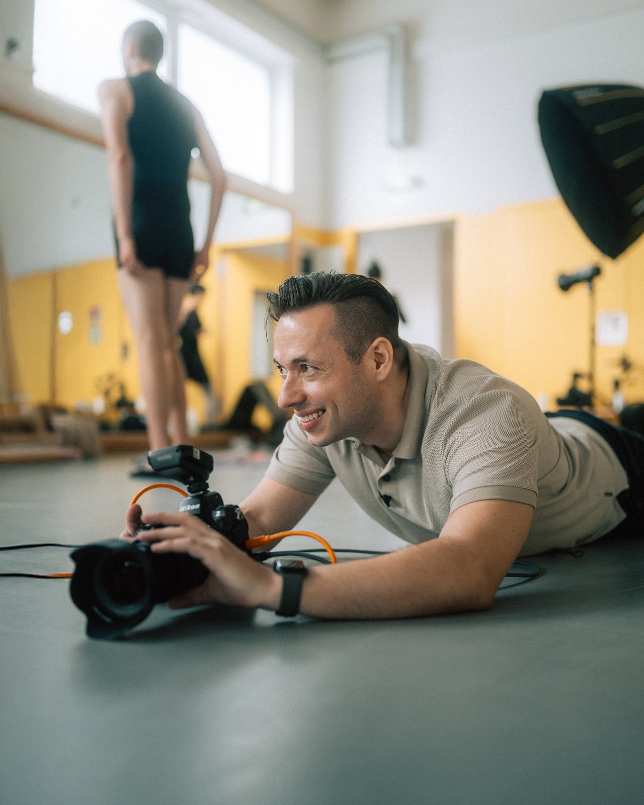 Tibor-Florestan Pluto smiling with his camera on the studio floor.