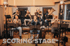 Bläserensemble mit neun Musikern, die im Klangfabik Studio spielen, mit Text "SCORING STAGE" im Vordergrund.