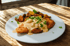 Gebratenes Hähnchen mit cremiger Soße und Rosmarinkartoffeln auf einem weißen Teller.