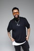 Ein lächelnder Mann mit Vollbart - Hussein Saleh -, gelber Sonnenbrille, Tattoos und schwarzem T-Shirt mit der Aufschrift Hussein Saleh.