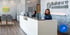 Receptionists smile behind a sleek white desk at Balance Wellspace.