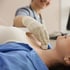 Medical professional performing a neck ultrasound for thyroid health on a female patient