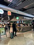 Flughafen-Food-Court mit Starbucks, Burger King und Menschen, die herumgehen oder sitzen.