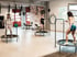 Drei Frauen trainieren auf Trampolinen im Kursraum eines Fitnessstudios.