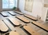 Ein Yogastudio mit Holzboden und mehreren schwarzen Matten mit ovalen Holzbrettern darauf.