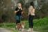 Eine Hundetrainerin spricht mit einer Kundin, während ein Shetland Sheepdog an der Leine auf einem Feldweg steht.