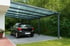 Ein schwarzes Auto steht unter einem modernen Carport aus Metall und transparentem Dach.