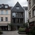 Modernes, dunkelgraues Giebelhaus mit Holzverkleidung und großen Fenstern zwischen zwei hellen Gebäuden.