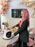 Jovana Babic schneidet einen rosa-weißen Kuchen mit "JUNIQUE BEAUTY" Logo
