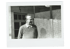 Schwarz-Weiß-Foto eines Mannes mit Brille und gemustertem Pullover, der zur Seite blickt.