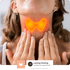Woman touching her throat, thyroid gland highlighted in orange and yellow to show inflammation.