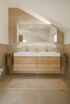 Modernes Badezimmer mit Doppelwaschbecken aus Holz und weißer Platte, großem Spiegelschrank und beiger Fliesenwand.