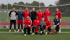 Elf Fußballspieler, einige kniend, stehen vor einem Tor auf einem grünen Feld.