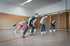Fünf Kinder in Sportkleidung bereiten sich in einer Turnhalle auf ein Rennen vor.