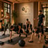 Personaltrainer leitet vier Personen beim Krafttraining mit Hanteln und Kettlebells im Fitnessstudio an.