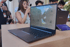 Laptop-Präsentation auf Messe oder Konferenz mit Besuchern und Demonstrationsbildschirm im Hintergrund.