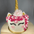 Einhorn-Torte mit rosa und pinkfarbenen Rosetten, goldenem Horn, Ohren und geschlossenen Augen.
