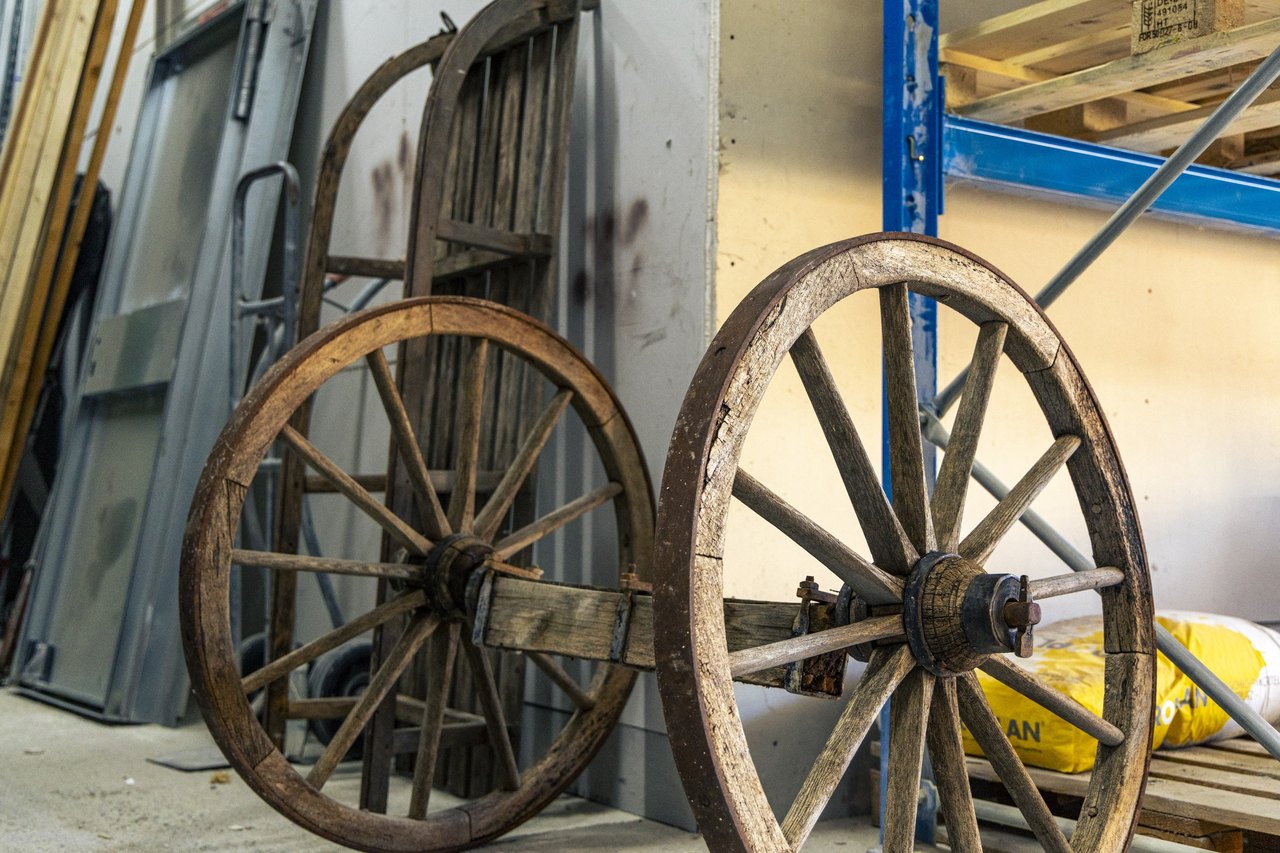 Zwei alte hölzerne Wagenräder mit Eisenreifen, an eine Wand im Lager gelehnt