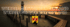 Leuchtturm am Steg bei Sonnenuntergang mit Text "WERBEAGENTUR BURGENLAND" und Wappen von Burgenland.