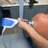 Therapist applying shockwave therapy to a patient's upper back 