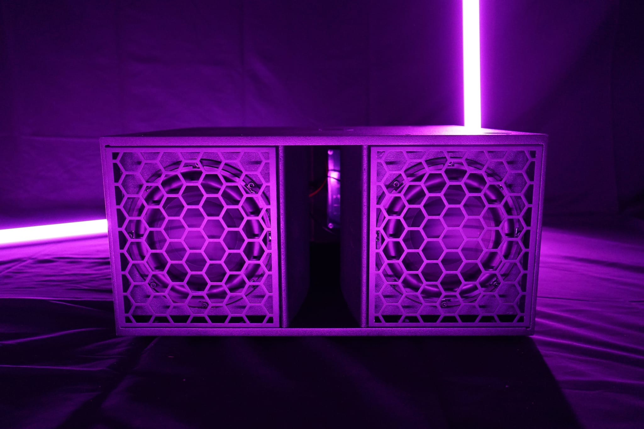 Moove Sub 208 from the front, both 8 inch woofers behind honeycomb grilles, lit in purple