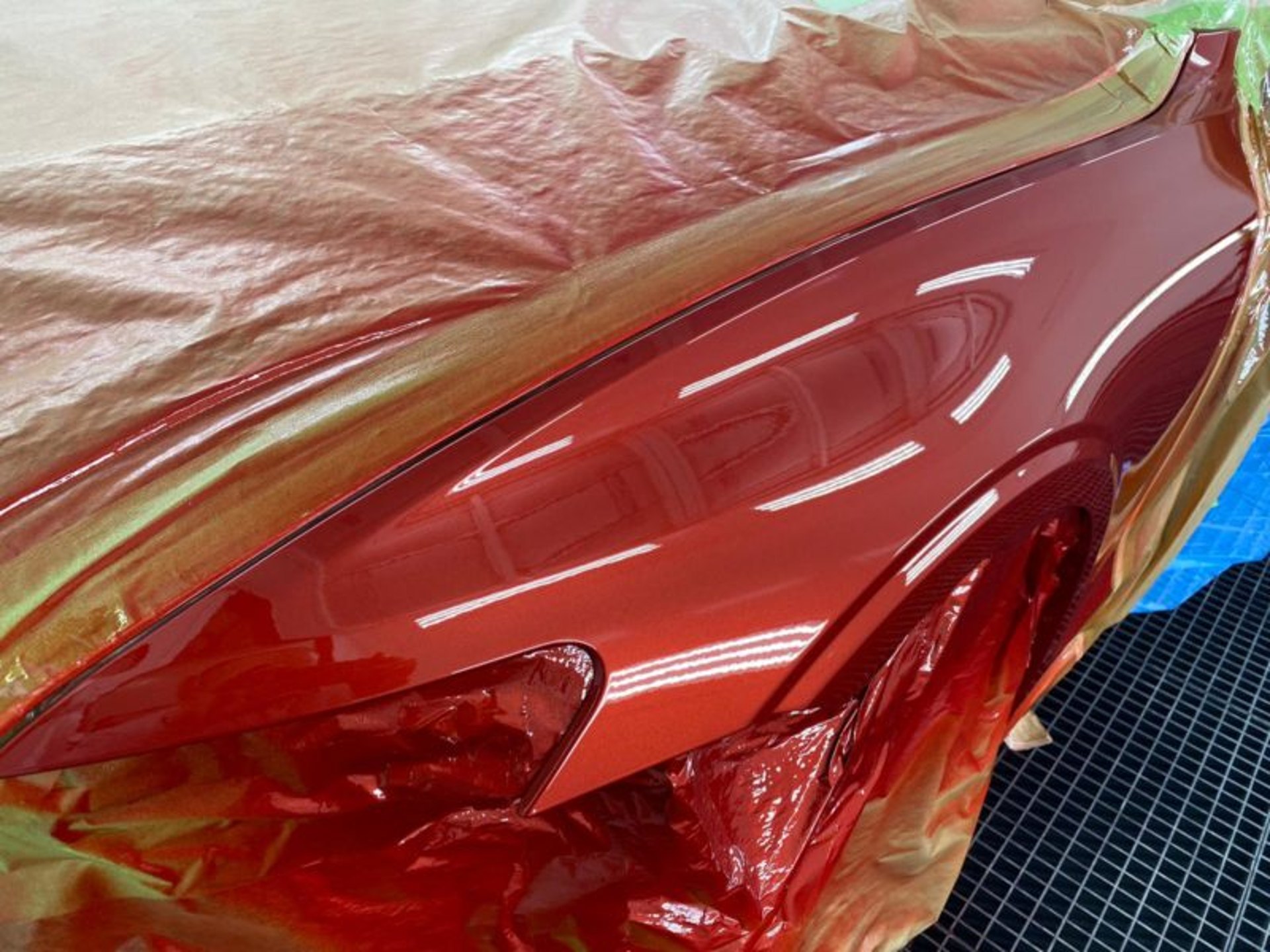 Rote Karosseriefläche unter Abklebefolie in Vorbereitung auf die Lackierung