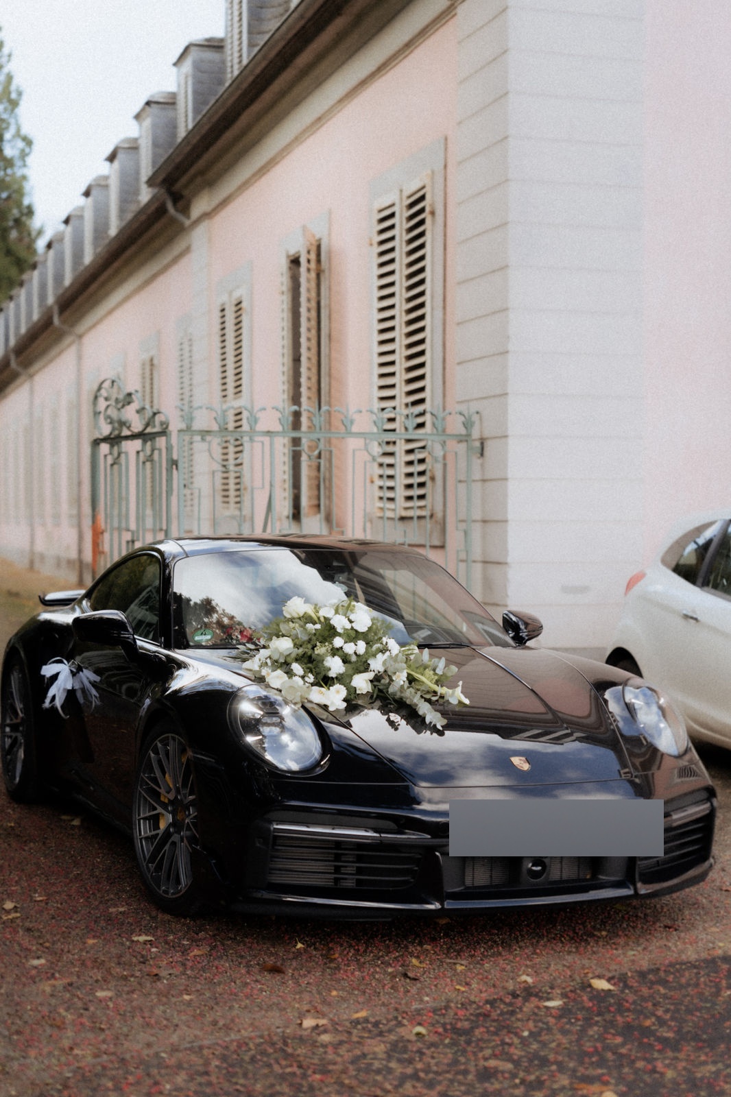 Schwarzes Hochzeitsauto mit Blumenschmuck vor Schloss Benrath in Düsseldorf.