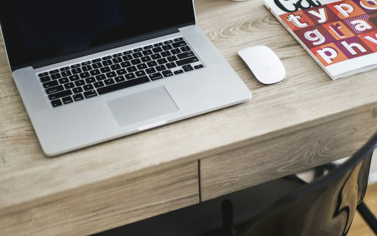 MacBook Pro mit Magic Mouse auf einem hellen Holzschreibtisch