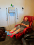 Man sits in a red recliner with his legs in red light therapy devices.