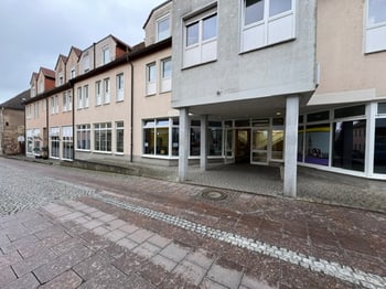 Gebäudezeile mit überdachtem Arkadengang an einer gepflasterten Fußgängerzone