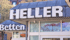 "HELLER" sign on a building with "Betten" below, reflecting a colorful display in its windows.