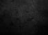 Dunkle, zerkratzte Oberfläche mit unebener Textur und leichten Glanzlichtern.