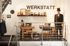 Ein Schaufenster mit dem Schriftzug "WERKSTATT" und einem Schaufensterpuppe in einem Frack und Zylinder.