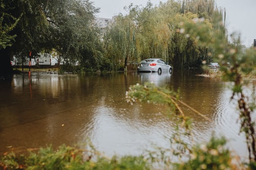 Flooded roads in Corona, CA: a car driving through standing water on a street after a heavy rainstorm