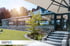 Ein Wintergarten mit Glaswänden und Markisen, daneben eine Terrasse mit Steintreppe und Sonnenschirm.