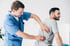 Chiropractor examining male patient for back pain