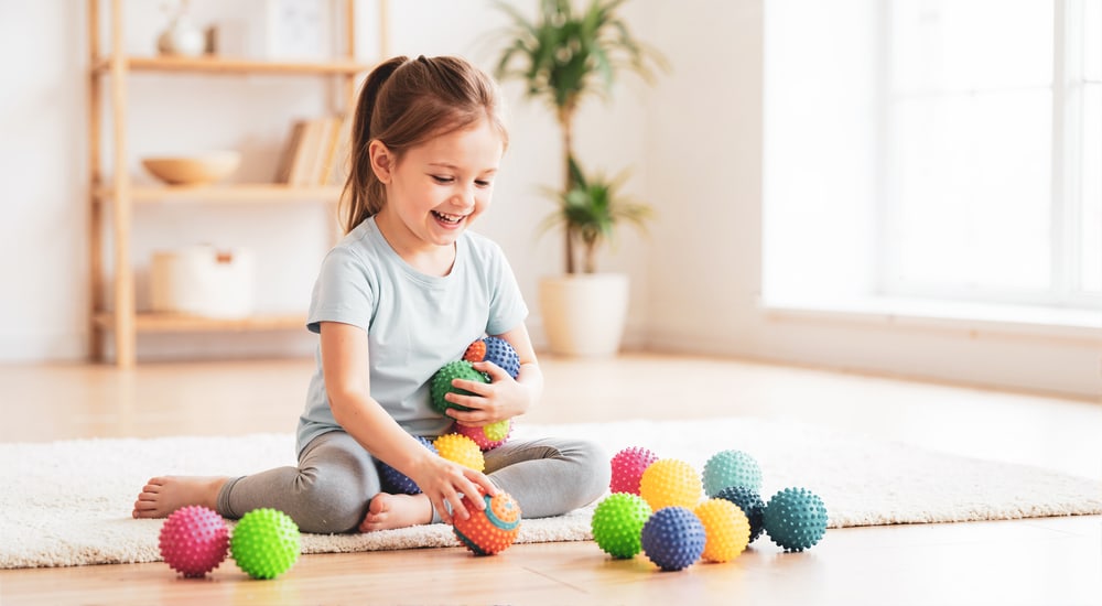 Mädchen spielt mit bunten Igelbällen