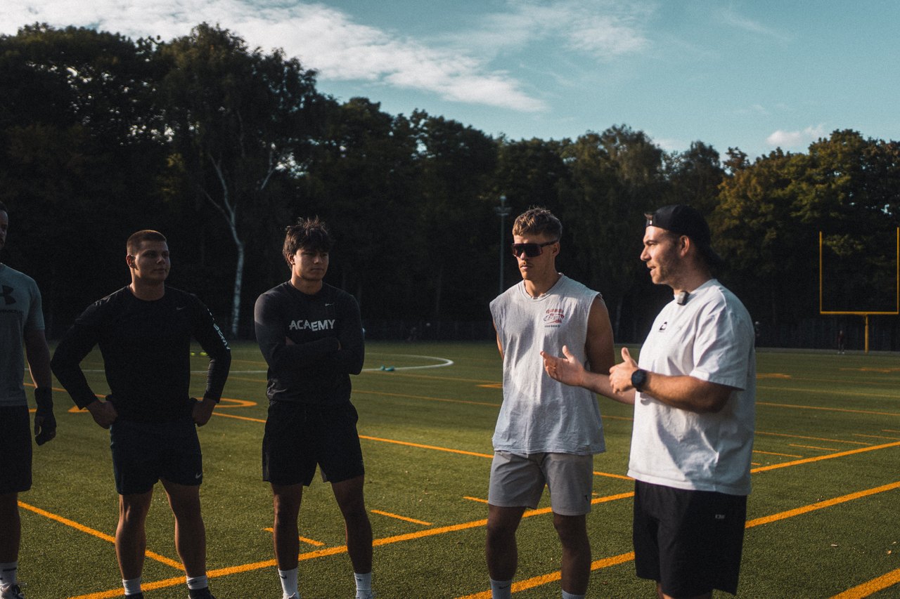 Coach spricht mit vier jungen Athleten auf dem Sportplatz