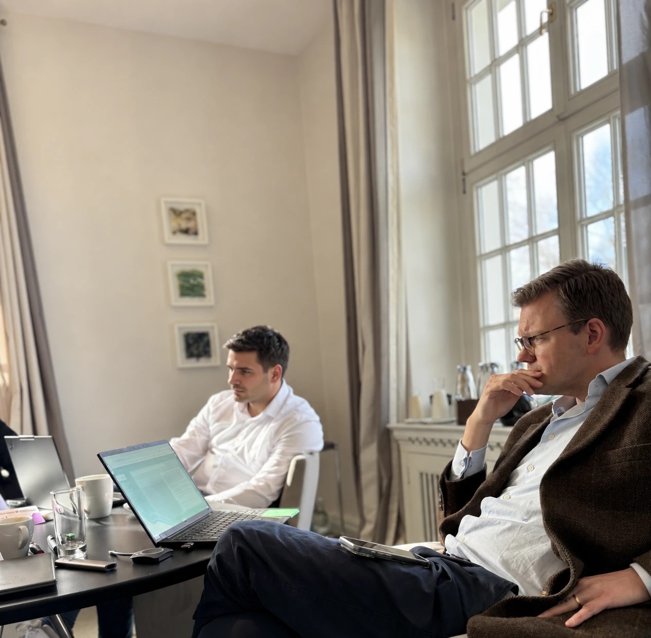 Zwei Teilnehmer verfolgen konzentriert eine Besprechung am Laptop