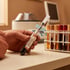 Gloved hands hold a blood sample vial labeled Biomarker Panel A next to a rack of test tubes and a centrifuge.