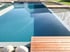 Moderner Naturpool mit Holzterrasse, klarem Wasser und einer bepflanzten Regenerationszone im Garten.