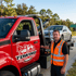 Towing Deltona flatbed towing service transporting a silver sedan with a tow operator beside the truck near the Deltona city limits