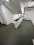 Ein leerer, sauberer Parkhauskellerraum mit glattem grauen Boden, weißen Wänden und einer „P“-Tafel.