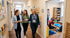 Drei Frauen unterhalten sich auf einem Flur im Kindergarten, während im Hintergrund Kinder und Erzieher spielen.