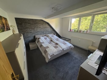 Schlafzimmer mit Doppelbett, Fenster und Dachschräge