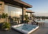 Jacuzzi auf einer Terrasse vor einem modernen Haus mit Glasfront, Infinity-Pool und Liegestühlen bei Sonnenuntergang.